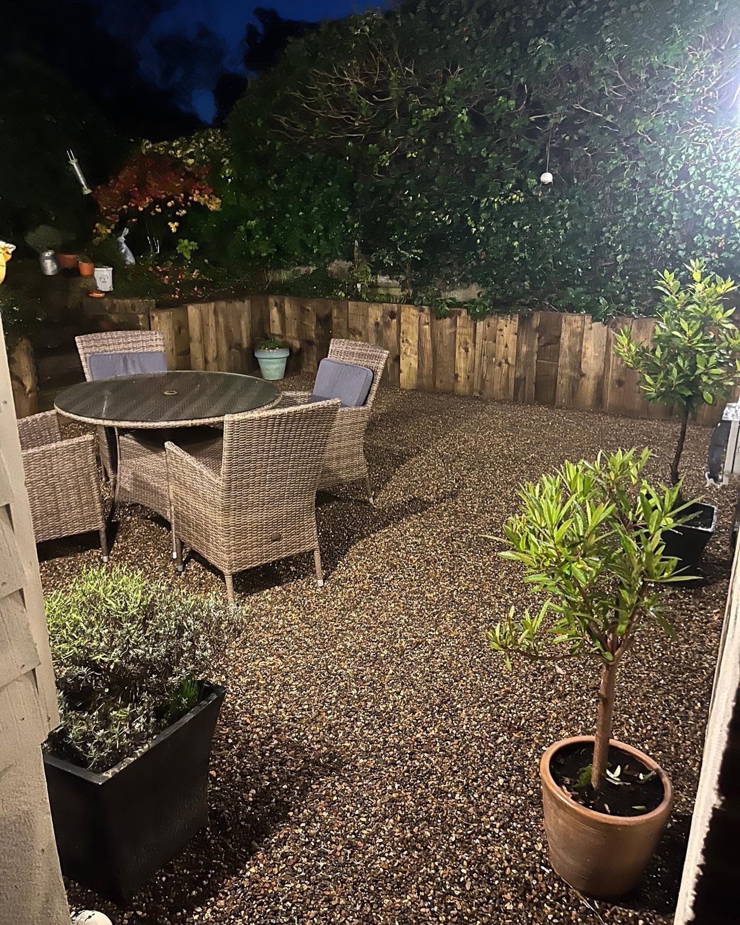 Lit gravel seating area with timber raised beds by Hawk Landscapes