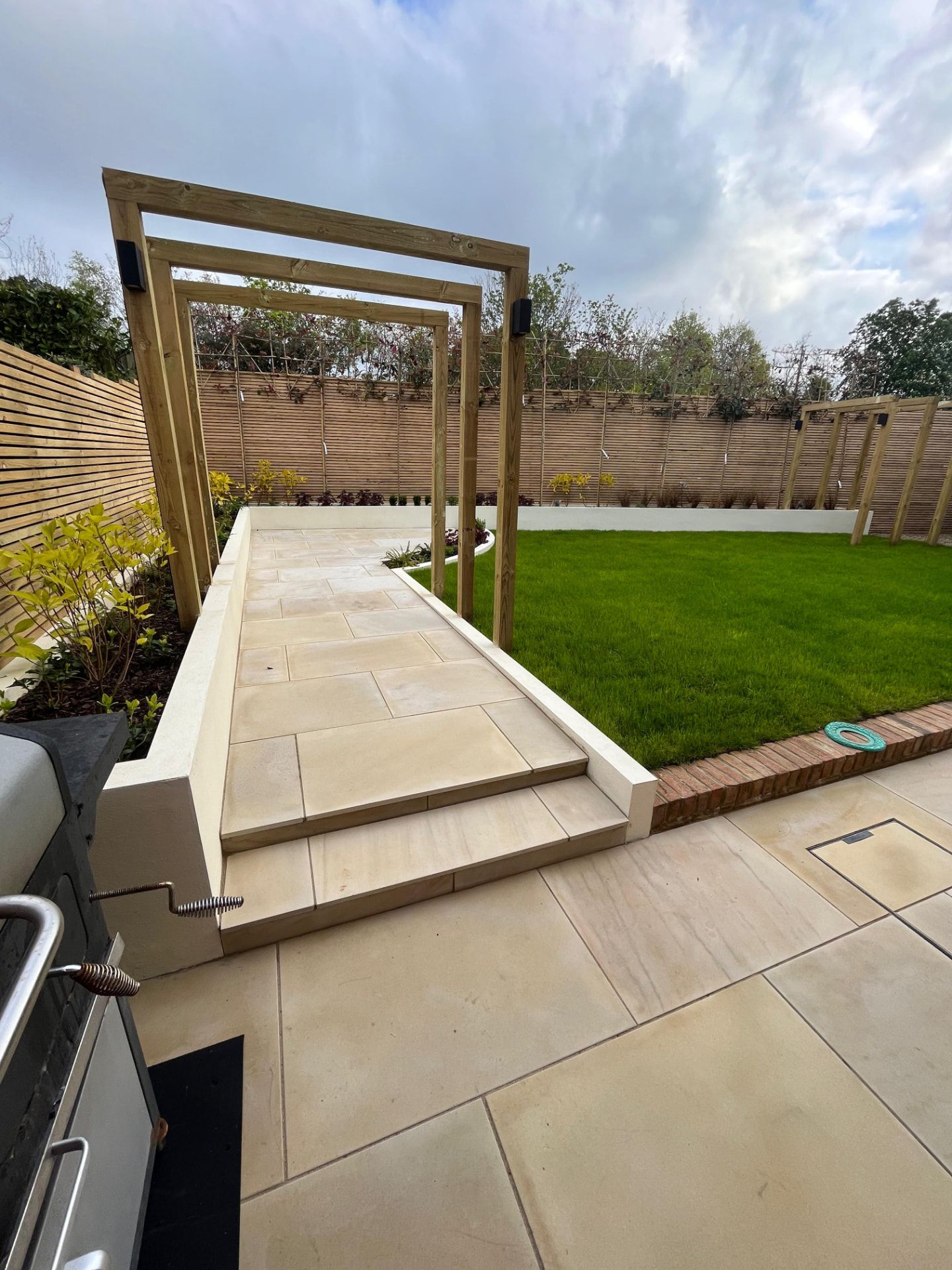 Completed Hawk Landscapes garden with sandstone patio, pergola frames and new lawn