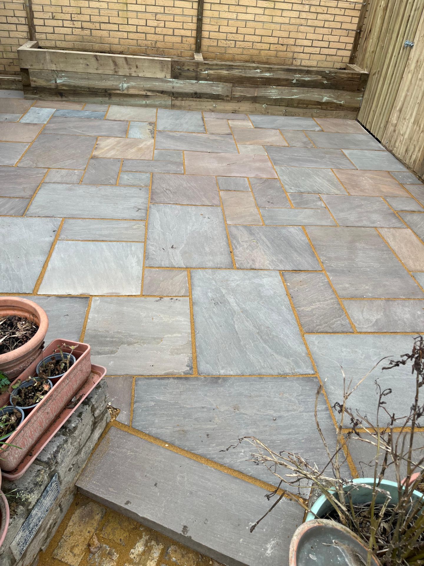 Indian sandstone patio with raised sleeper edging built by Hawk Landscapes